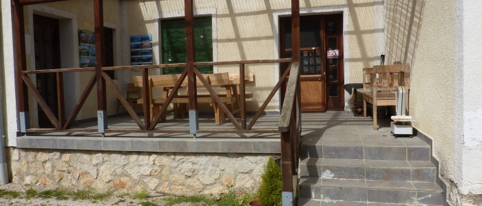 Az ugodi Árnyaserdő Turistaszálló épületbejárata padokkal és asztalokkal